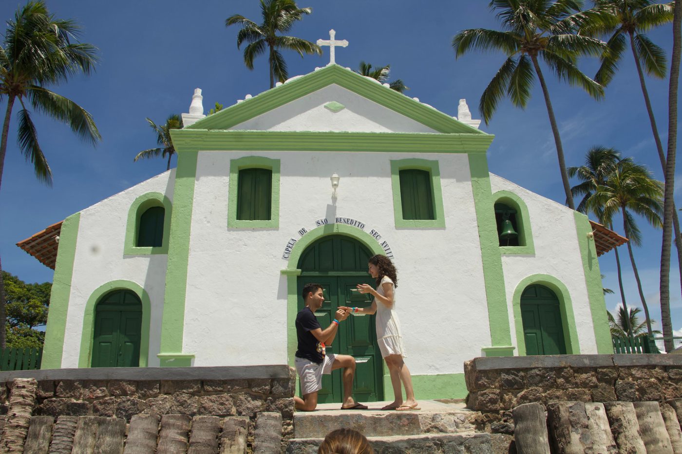 Vinícius ajoelhado pedindo Mariana em casamento em frente à Capela de São Benedito, em 1º de abril de 2024