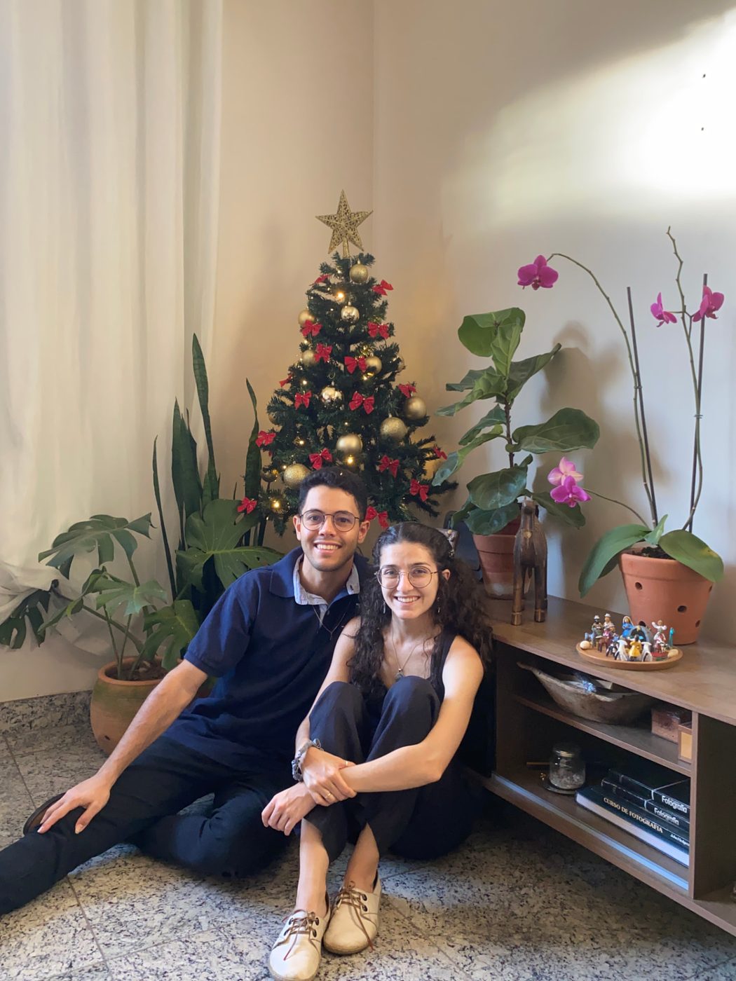 Mariana e Vinícius sentados perto da árvore de Natal na segunda casa do casal, em novembro de 2025