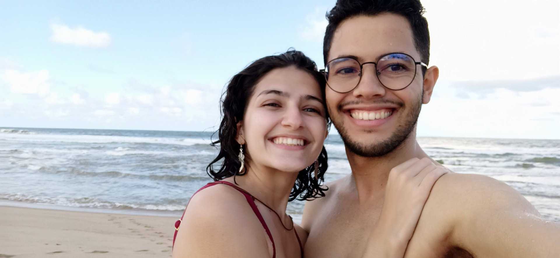 Mariana e Vinícius abraçados na praia durante a primeira viagem do casal, em setembro de 2021